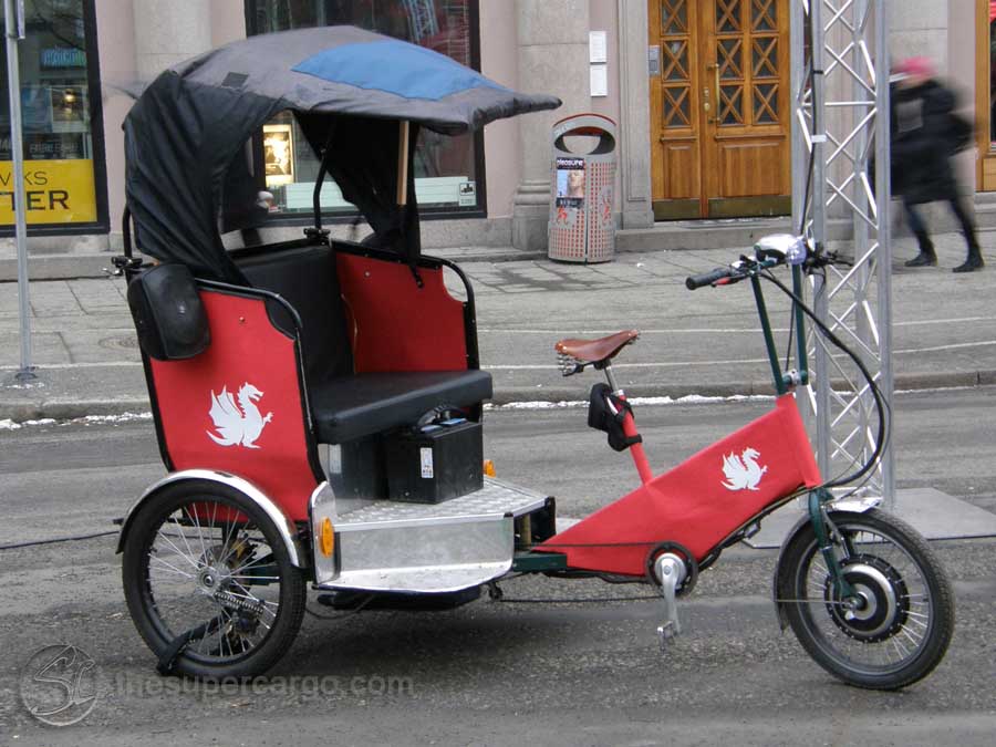 A pedal powered tricycle rickshaw with the dragon  logo of the Gothenburg International Film Festival parked outside the Pustervik temporary offices of the GIFF