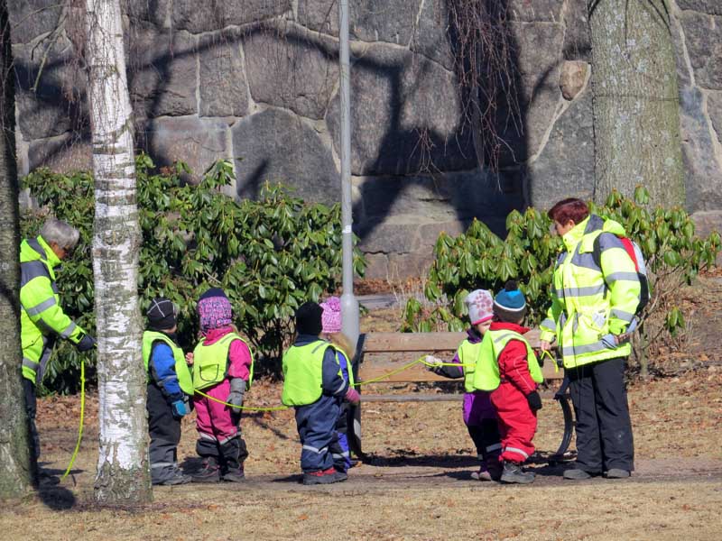 Kindergarten children and teachers in high vis jackets: The rope gang in the park