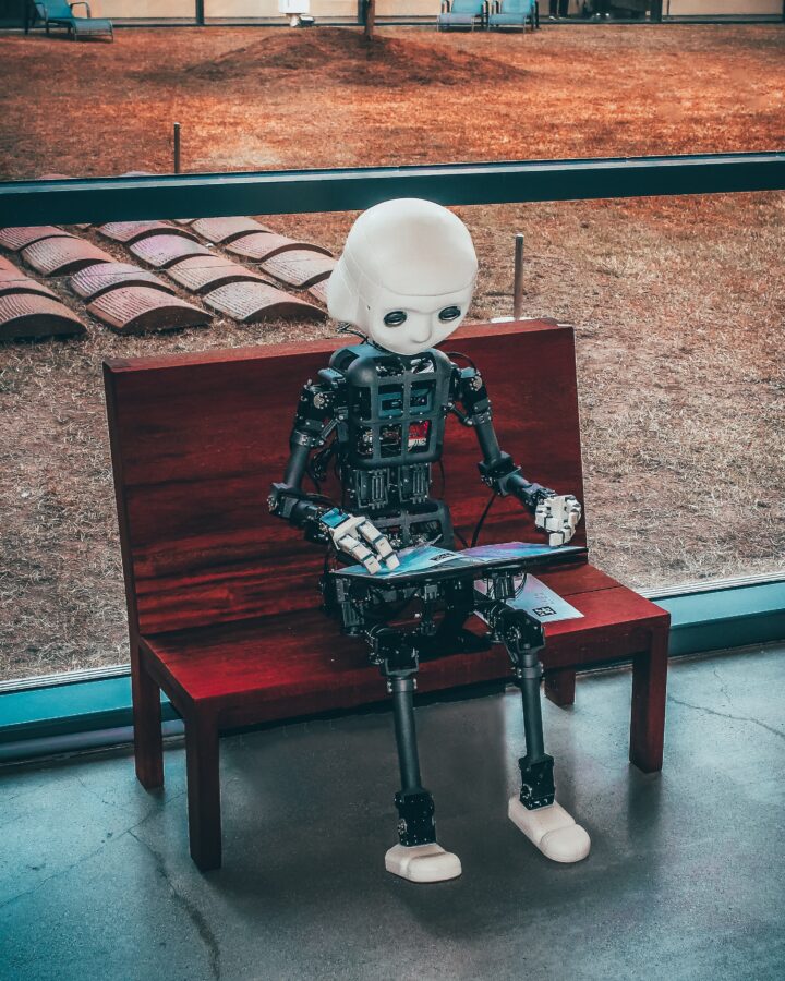 Machine translating: Robot on a bench reading a book