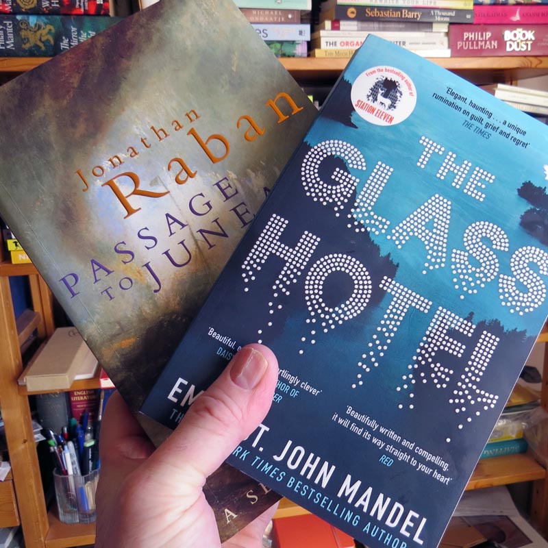 Covers of Passsage to Juneau and The Glass Hotel books held in my hand