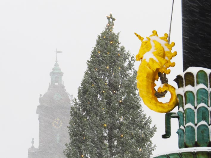 A golden sea-unicorn, Christmas tree and the tower of the Christina Church (Tyska kyrkan) seen through falling snow. Gustaf Adolfs torg, Göteborg. Photographed 8th December 2013.