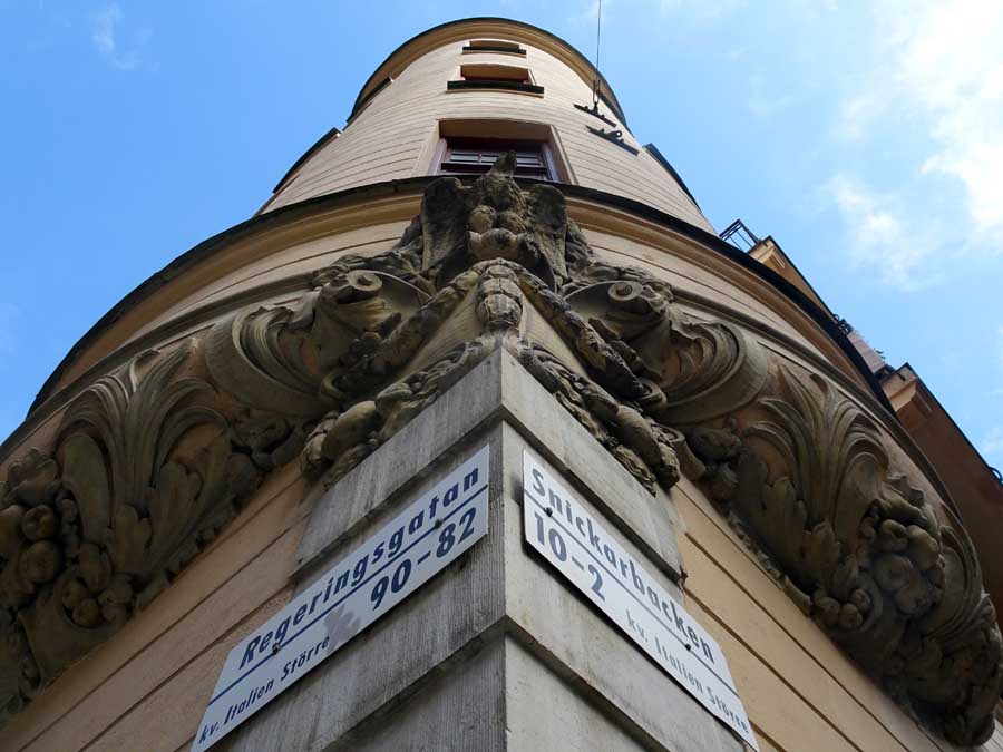 Corner tower - an architectural feature - photographed from an acute angle, the names of two street signs - for Regeringsgatan and Snickerbacken - can be seen.
