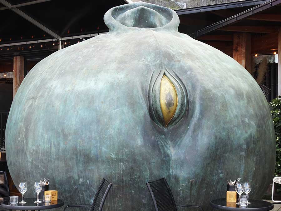 The massive head of a child on its side, with one golden eye and one pointed ear keeping watch over tables with wineglasses outside Stockholm's Fotografiska gallery